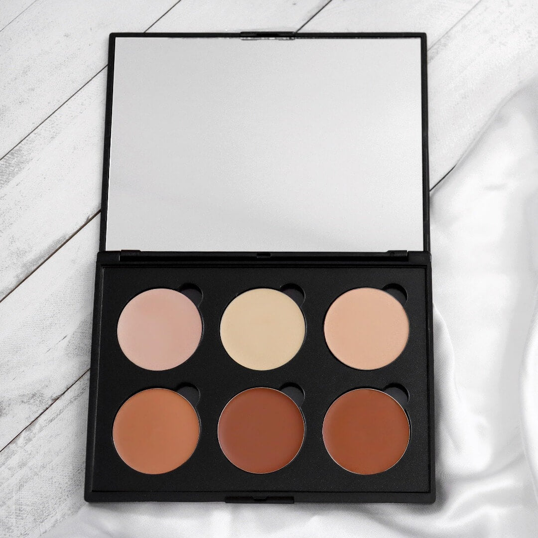 Image de la grande palette de contouring en crème ARTIST. La palette est ouverte et se retrouve dans un boitier noir. Cette palette contient 6 fards de modelage. Les trois fards du haut sont les fards illuminateurs beiges (rosé, jaune, orangé). Puis ceux du bas sont les 3 fards de modelage foncés. 