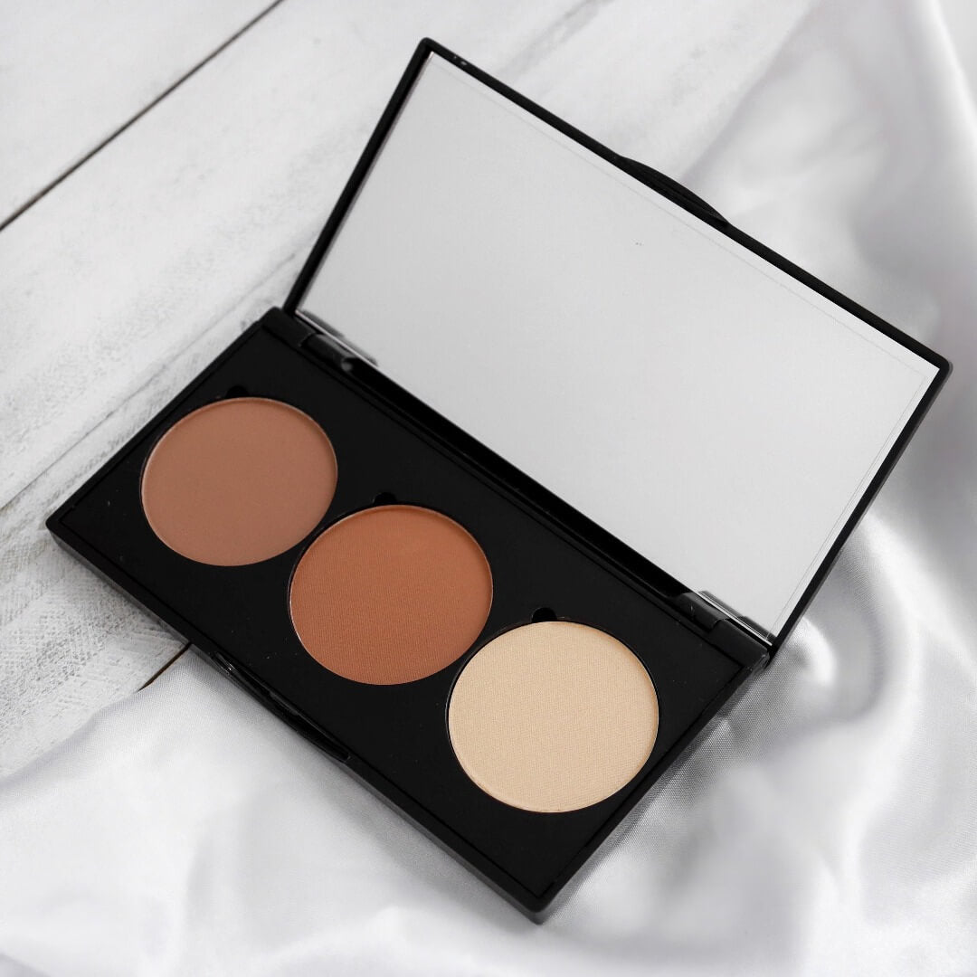 Photo de la palette de contouring en poudre ARTIST. À la droite se retrouve la teinte brun froid, au centre le brun chaud et à la droite le beige clair. Le tout dans un boîtier noir avec un miroir. 