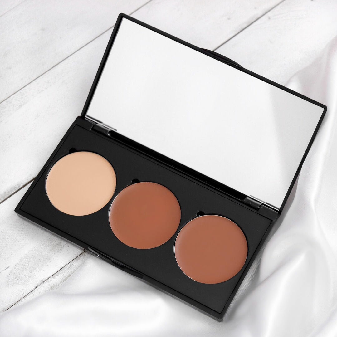 Photo de la palette de contouring en crème ARTIST. Il y a trois teintes. Teinte claire mate à la gauche, au centre la teinte brun chaud, et à la droite le brun froid. Le tout dans une palette noir.